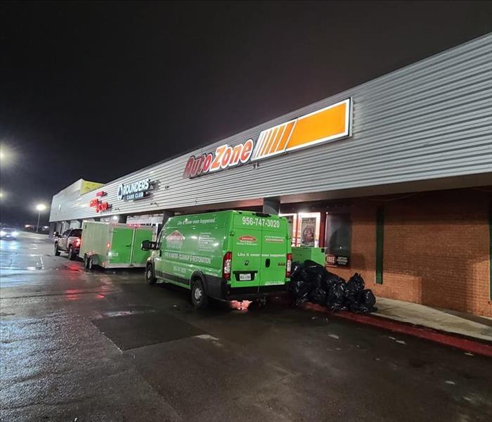 24/7 - image of green SERVPRO vehicles outside building